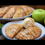 Caramel apple empanadas stacked on a rustic board
