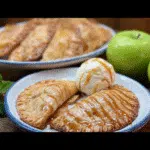 Caramel apple empanadas stacked on a rustic board