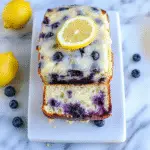 Lemon Blueberry Bread sliced on a rustic table with lemon glaze